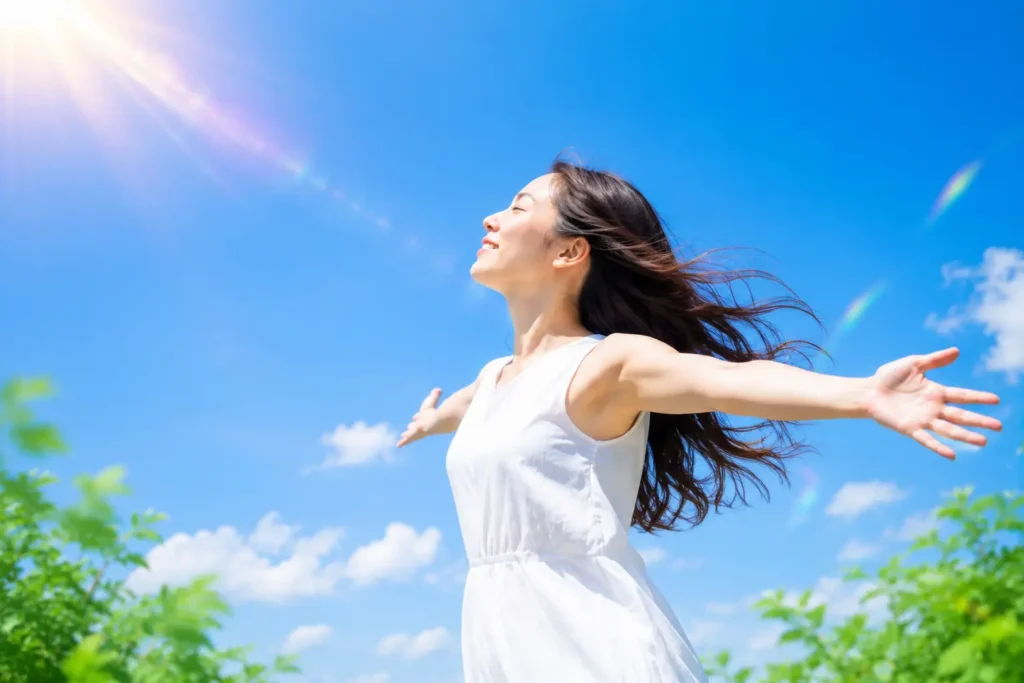 青空の下で心を開き、自分らしさを取り戻す女性のイメージ