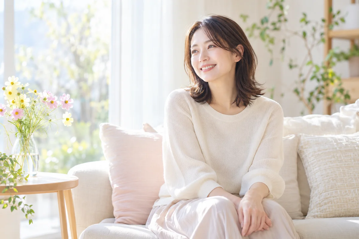 柔らかな日差しの入る室内で、ソファに座り穏やかに微笑む女性